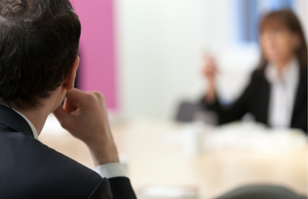 Close-up of  a barrister listening to a woman in the background.