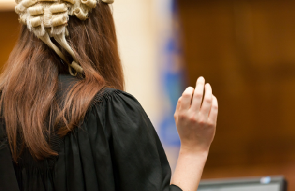 Woman barrister with a wig and gown in court.